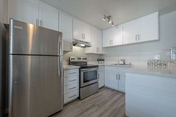 A white kitchen with stainless steel appliances and white cabinets